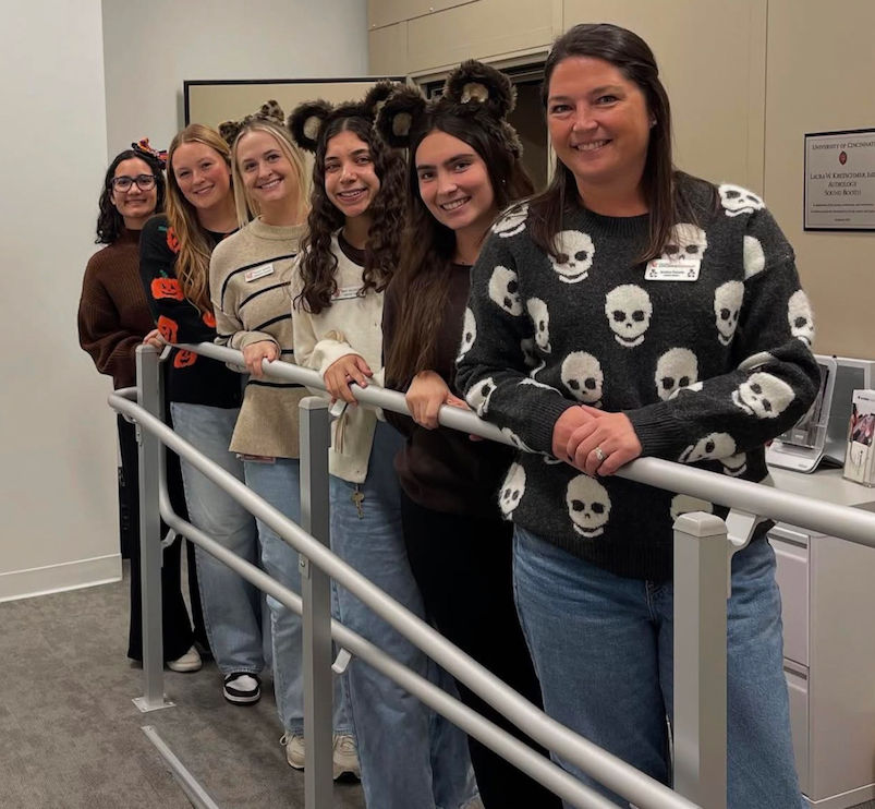 Graduate students and a professor line up inside the Speech & Hearing Clinic wearing costume ears for Halloween