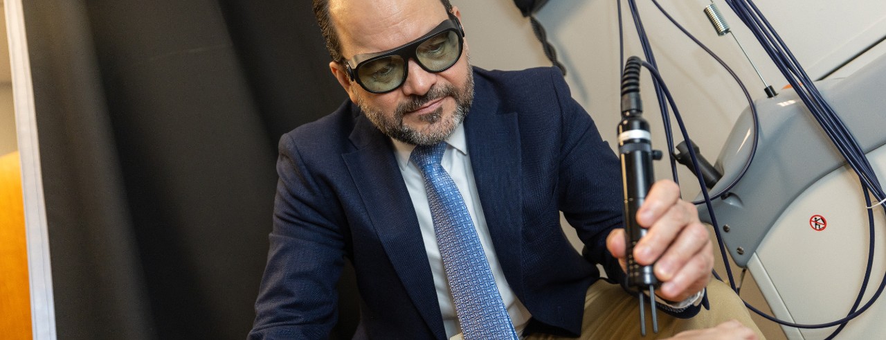 Francisco Romo-Nava holds a pen-like device in his hand that administers a laser signal to a participants' foot