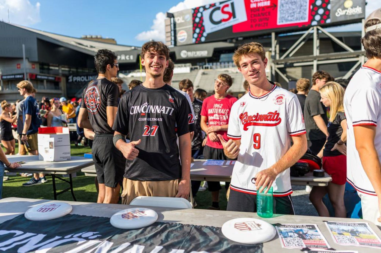image two male students wearing UC gear standing among many students in Nippert Stadium for a Student Involvement Fair