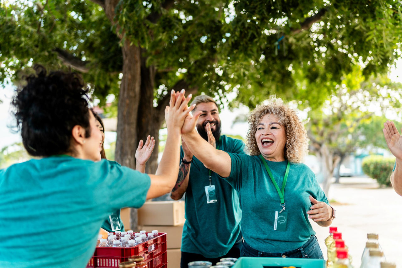 Two female volunteers give each other a high five while outside staffing a table