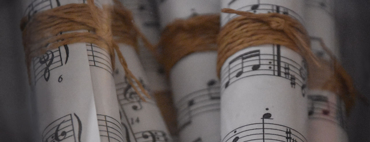 A decorative stock image of paper scrolls of music manuscripts. Photo licensed from iStock by Getty Images.