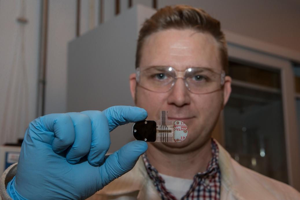 With a gloved hand, Adam Hauke holds up a skin sensor in front of his face for a closeup.