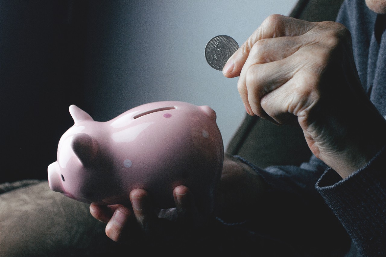 Person putting a coin in a piggy bank