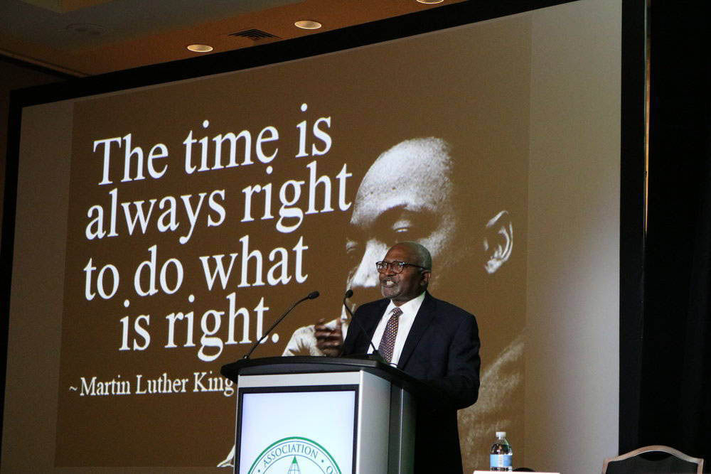 Dr. Bullard standing in front of a screen displaying Dr. Martin Luther King and the quote "The time is always right to do what is right."