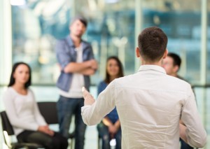 Five people sit before a counseler in community-based rehabilitation.