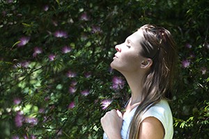 woman looking in sun with eyes closed and a flower in her hand