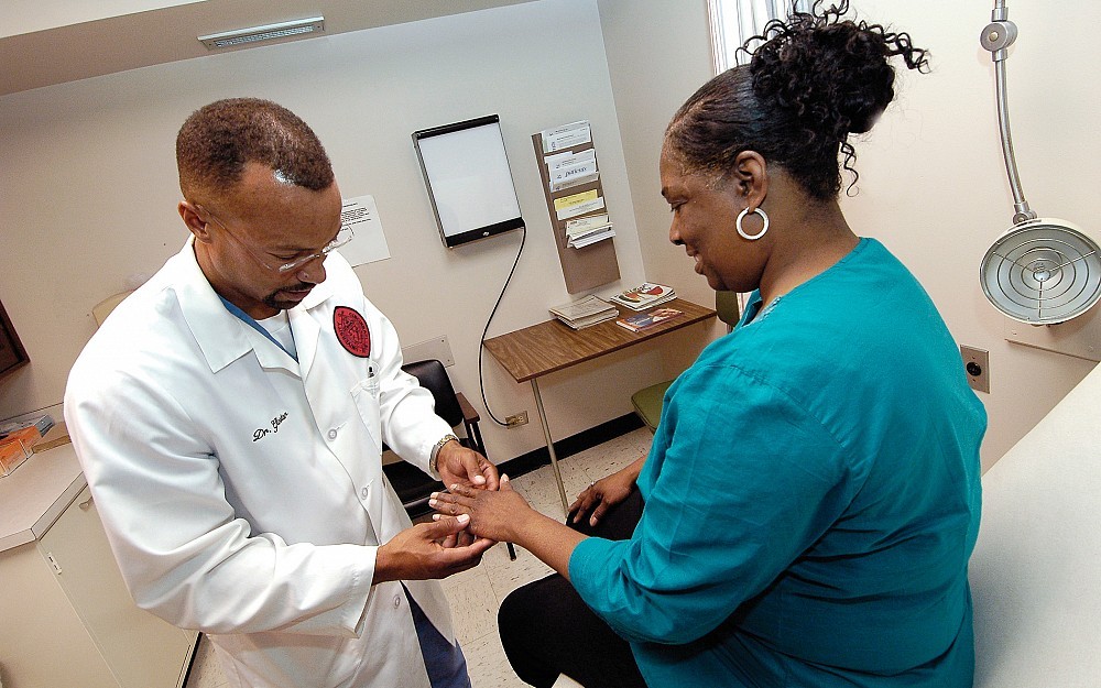 Hugh Gloster, MD, examines the skin of a patient. His recent research stresses that all people are at risk for skin cancer, regardless of skin type.