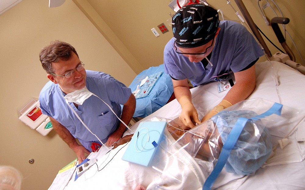 Gerald Kitchens, MD, (right) inserts a continuous nerve block catheter into a patient of orthopedic surgeon Keith Kenter, MD, (left).