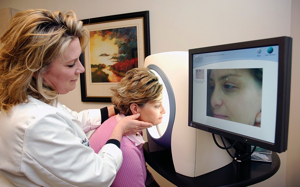 Medical skin care specialist Cathy Fricke (left) conducts a skin analysis on a patient.