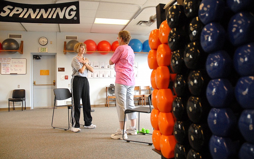 A ftness instructor works with a breast cancer survivor on an exercise routine. 