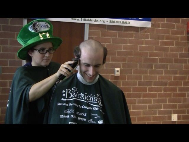 Second-year medical student Meredith Baker takes her barber job very seriously as first-year student Derek Douglas loses his locks...with a smile on his face on St. Baldrick's Day 2011. 