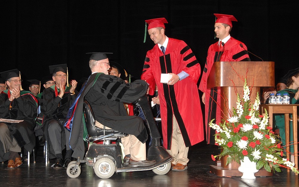 2011 medical school graduate John Szymusiak, MD, (standing) shakes hands with John Quinlan, MD, a professor in the deparment of neurology, as Quinlan receives the Silver Apple Award bestowed upon him by second-year medical students for excellence in teaching.    