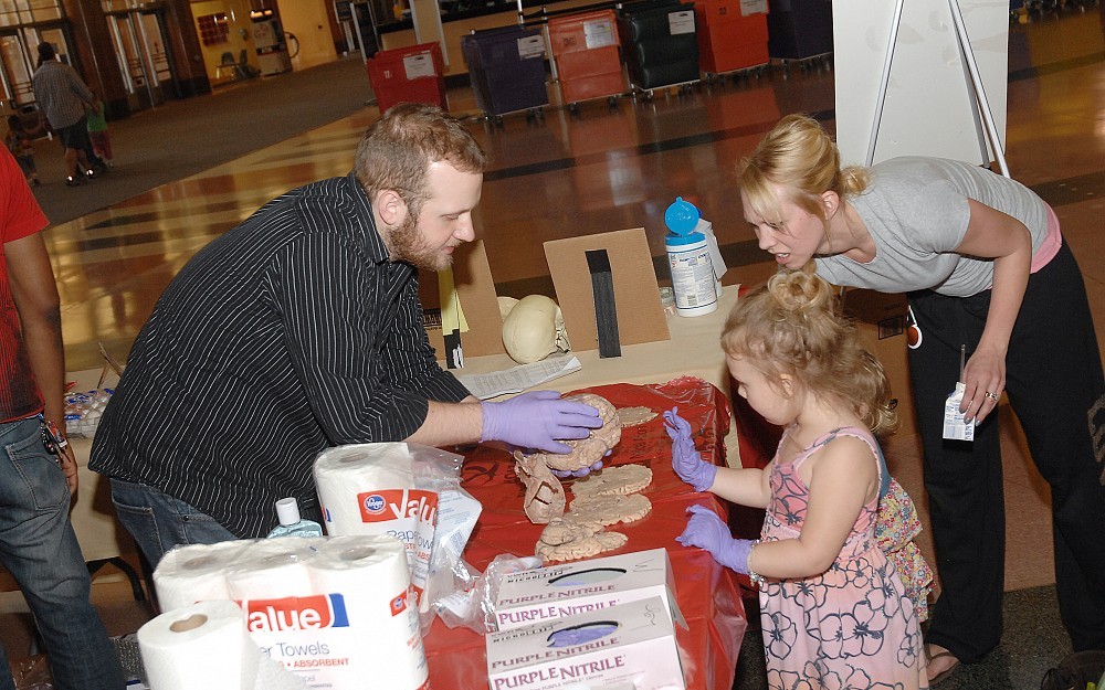 Neuroscience graduate student Joe Korfhagen shows a human brain to Taylor Dartnall and her mother, Alicia Dartnall.