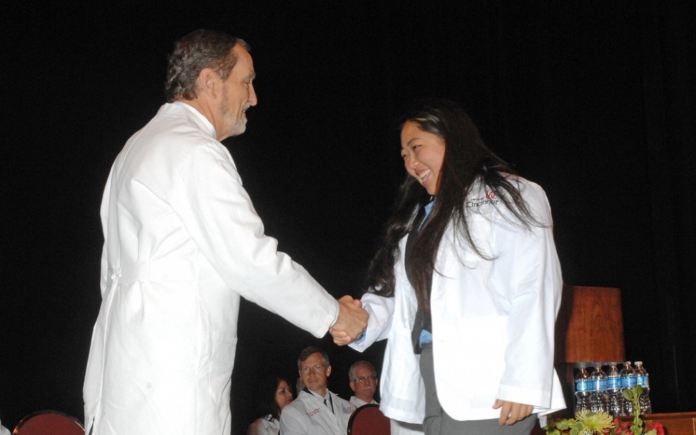 A student in the college of medicine class of 2016, Karen Chao shakes hands with Dean Thomas Boat, MD, after receiving her white coat.