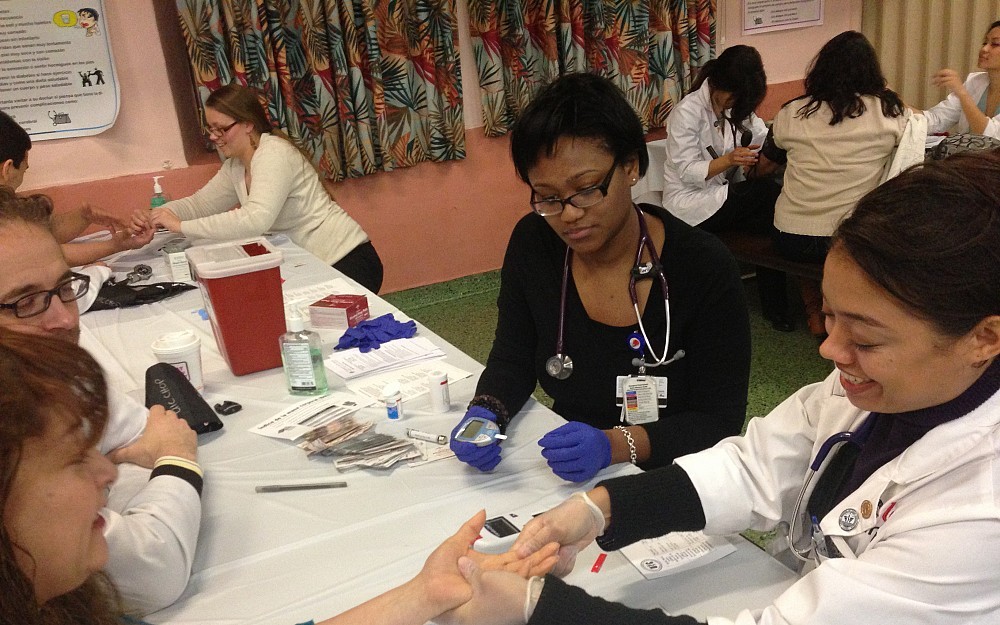 UC LMSA students Danielle McCarthur (in black) and Antonia Susarret (in a white coat) volunteer at a health fair during the LMSA Midwest conference.