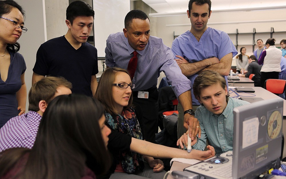 Lester Duplechan, MD, places a transducer on the wrist of resident Rachel Blankenship, DO, while a team of first-year medical students study her ultrasound.