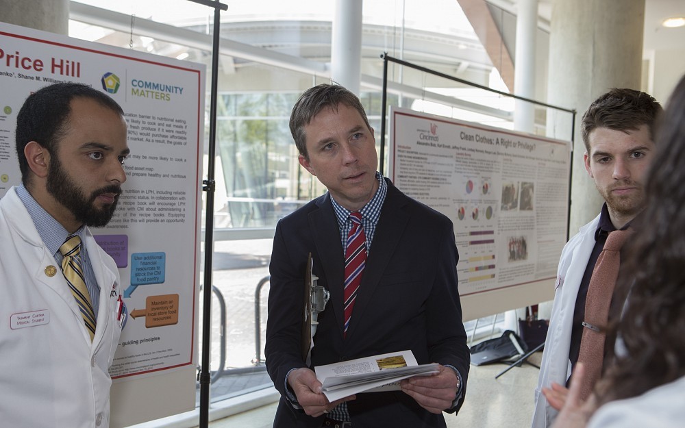 Joseph Kiesler, MD, associate professor in the Department of Family and Community Medicine, center, speaks with medical students during a poster presentation in CARE/Crawley Atrium.