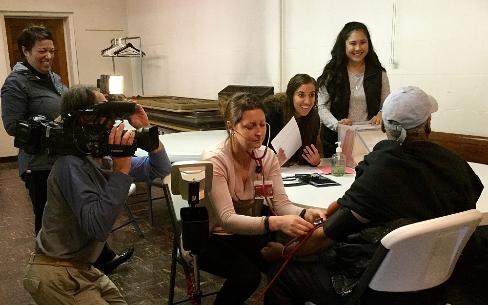 UC College of Nursing students performing health screenings and education at the Food for the Soul soup kitchen at St. John AME Zion Church in Avondale with Valorie Grant looking on to the left. The students from left to right are Luliana Braga, Jennifer Murphy and Tess Akgunduz.
