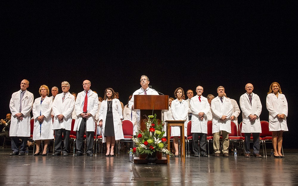 College of Medicine Dean William Ball is joined on stage by UC Interim President Beverly Davenport (immediate left) and College of Medicine faculty members.