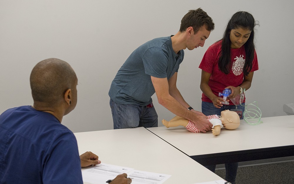 First-year med students Ben Wissel and Farah Hussain demonstrate their first-responder training in the College of Medicine. Reginald Fennell, a paramedic and nurse, looks on.