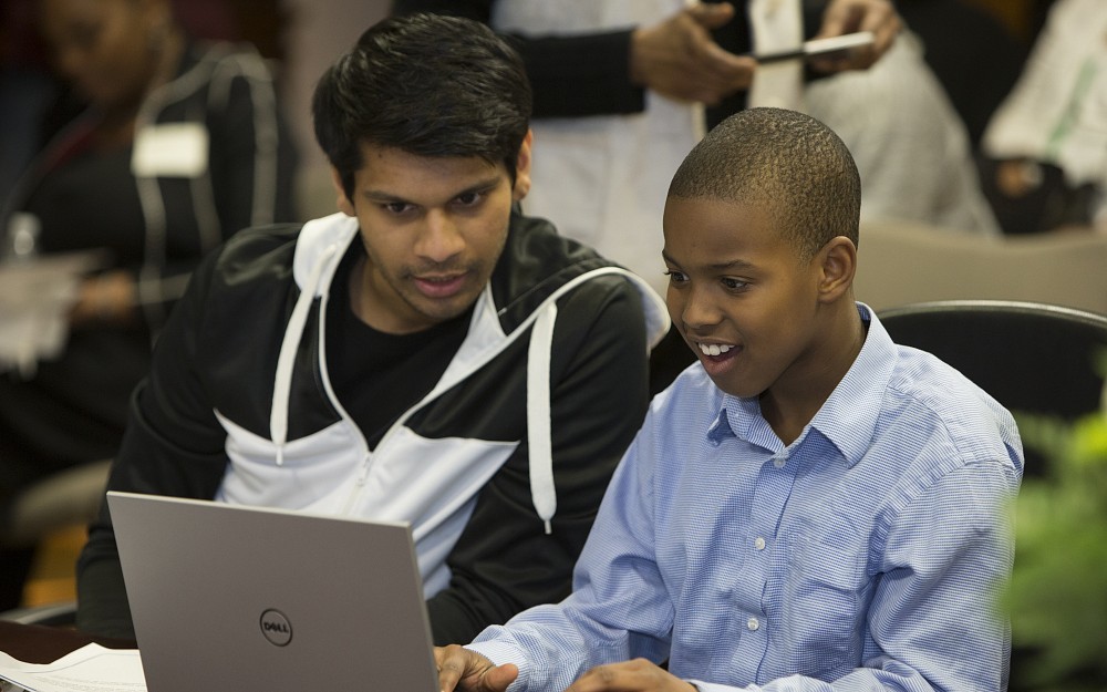 Medical student Neeraj Maheshwari assists his mentee, Lonell Williams, with a new laptop from UC Med Mentors.