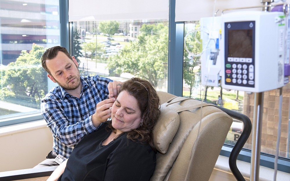Derek Johnson, a licensed acupuncturist with UC Health, spends Fridays in the Center for WomenÂ s Cancer on the third floor of the Barrett Center, where he offers ear acupuncture in the infusion suite to patients and families.