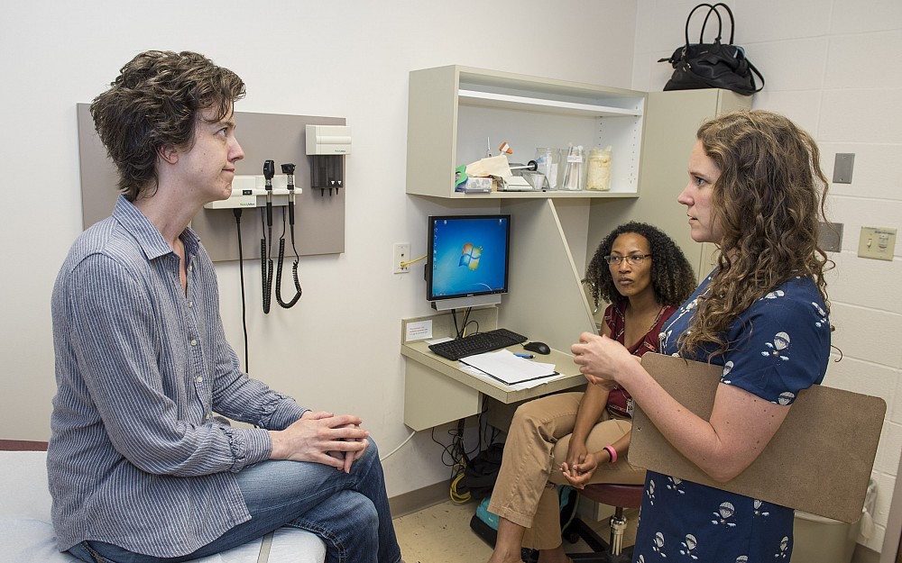 First-year resident Kate Singer, MD, (front right) is shown speaking with a standardized patient during her BRACK evaluation in the College of Medicine's Simulation Center. In the background is Sharice Woods, MD, observing. 
