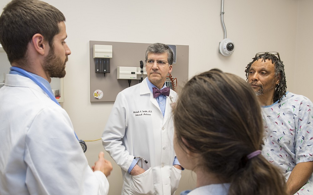 
Michael Sostok, MD, (center) is shown with two medical students and Heru Lasana, a standardized patient (rear), in the Simulation Center.
