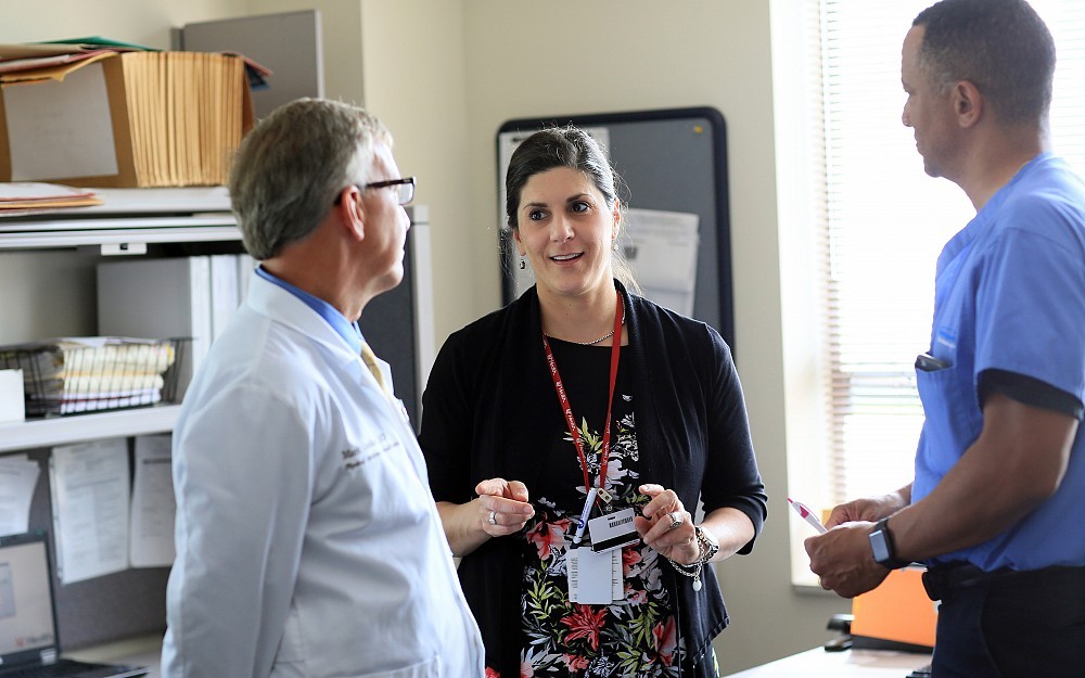 Angela Stillwagon, DO, assistant professor of the Department of Neurology and Rehabilitation Medicine, talks with Mark Goddard, MD (left) and Lester Duplechan, MD (right)