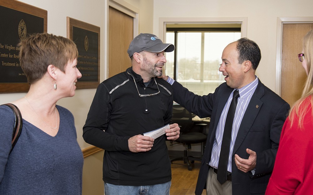 Scott layman, center, and his wife Joy, present the funds raised from Putting for Parkinson's to Alberto Espay, MD, Director of the Gardner Center for Parkinson's Disease and Movement Disorders