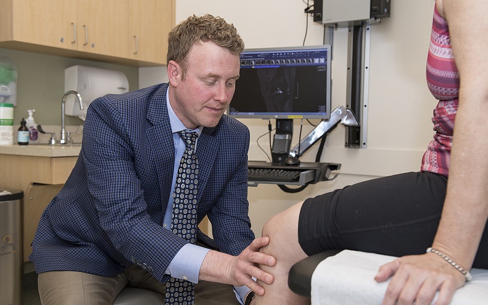 Brian Grawe, MD, examines a patient with knee osteoarthritis
