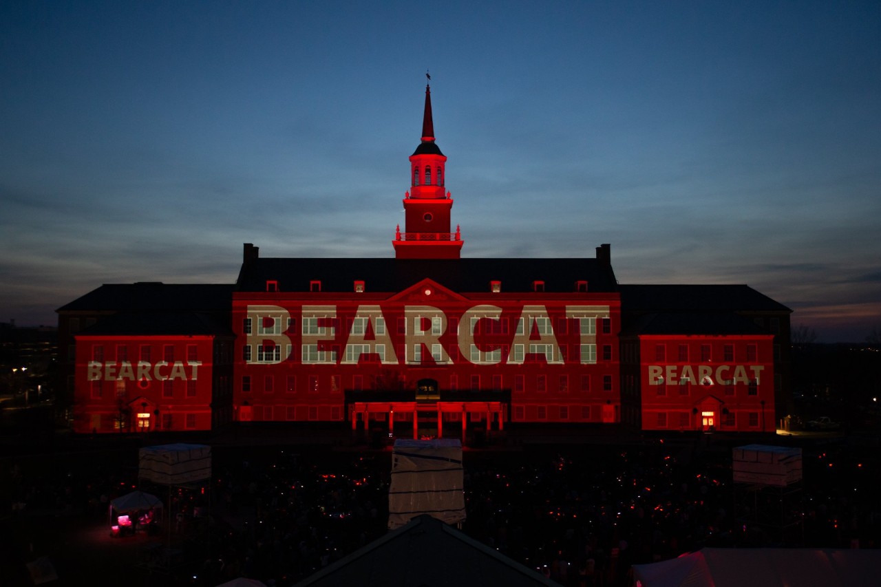 The word "Bearcat" projected on UC building at twilight