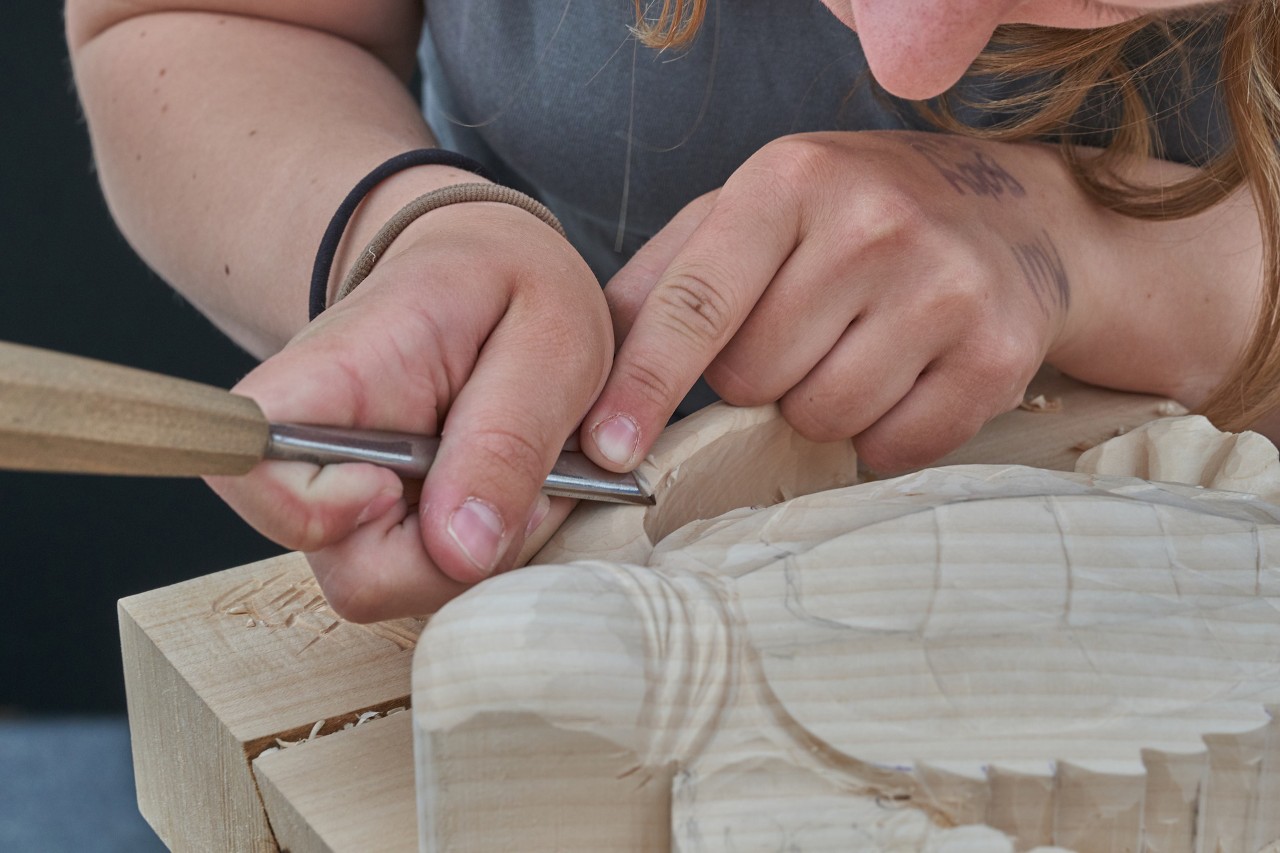 a close-up of a pair of hands carving wood.