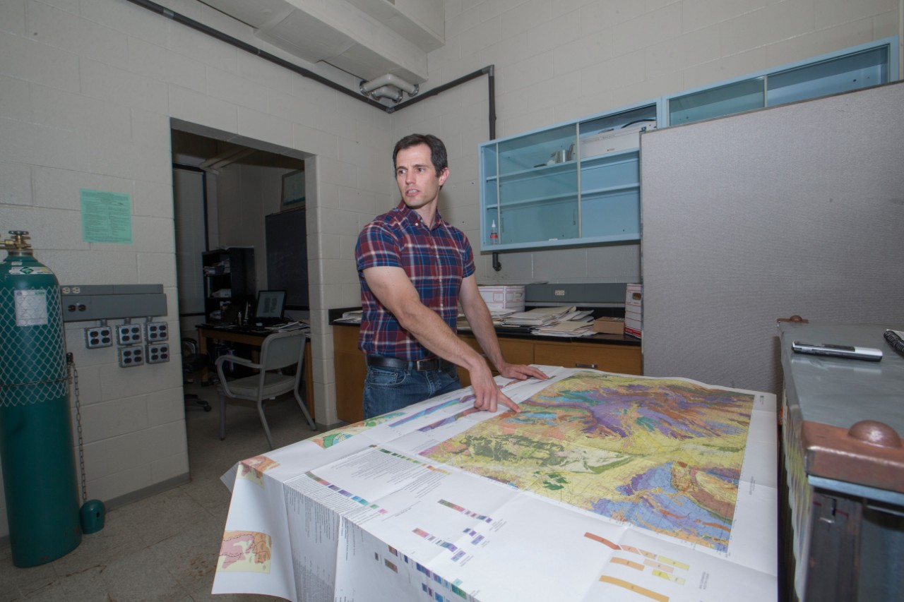 Geologist Daniel Sturmer stands over a map showing the geology of Nevada's Basin and Range.