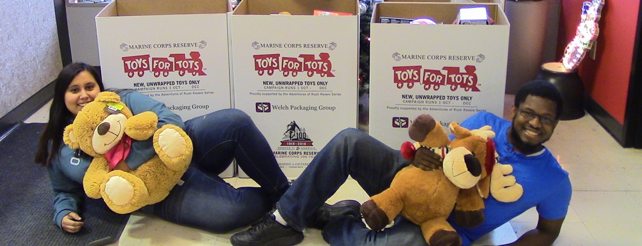 Two people pose with teddy bears and toy donation boxes