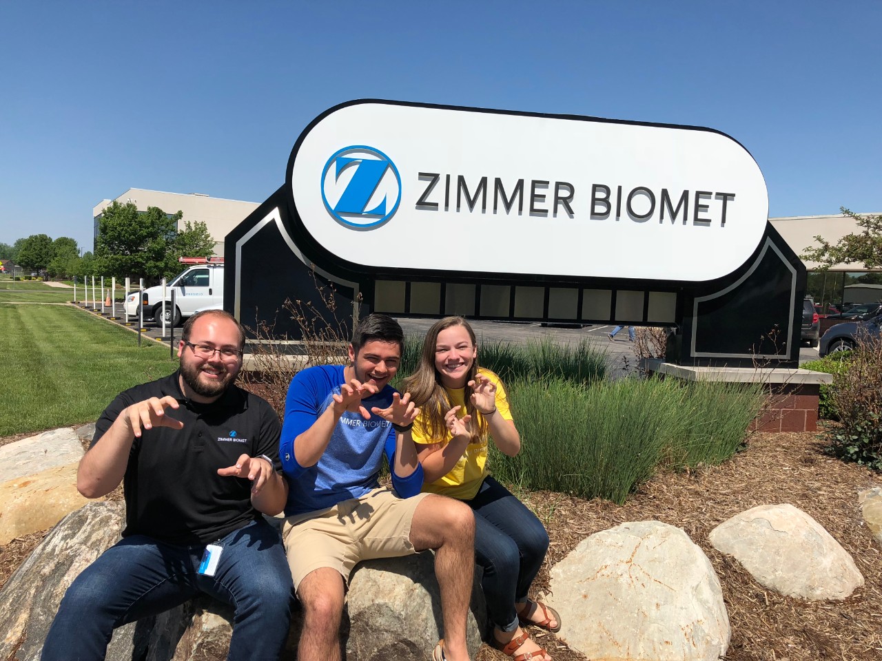 Goodwin and two friends in front of Zimmer Biomet sign outside.
