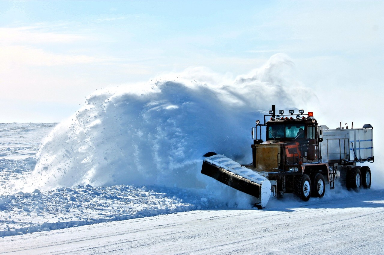 truck with snow plow pushes snow off the road