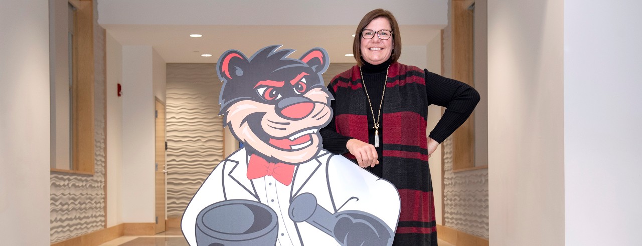 Kelly Epplen standing with Bearcat cutout at College of Pharmacy