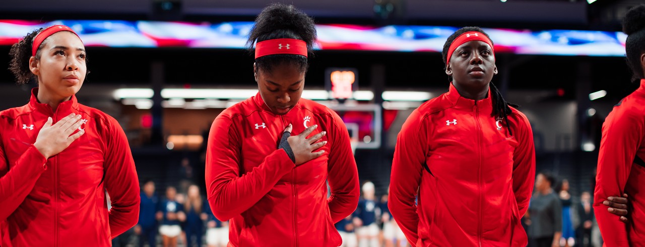 The UC women's basketball team looks on during the Anthem before a game.