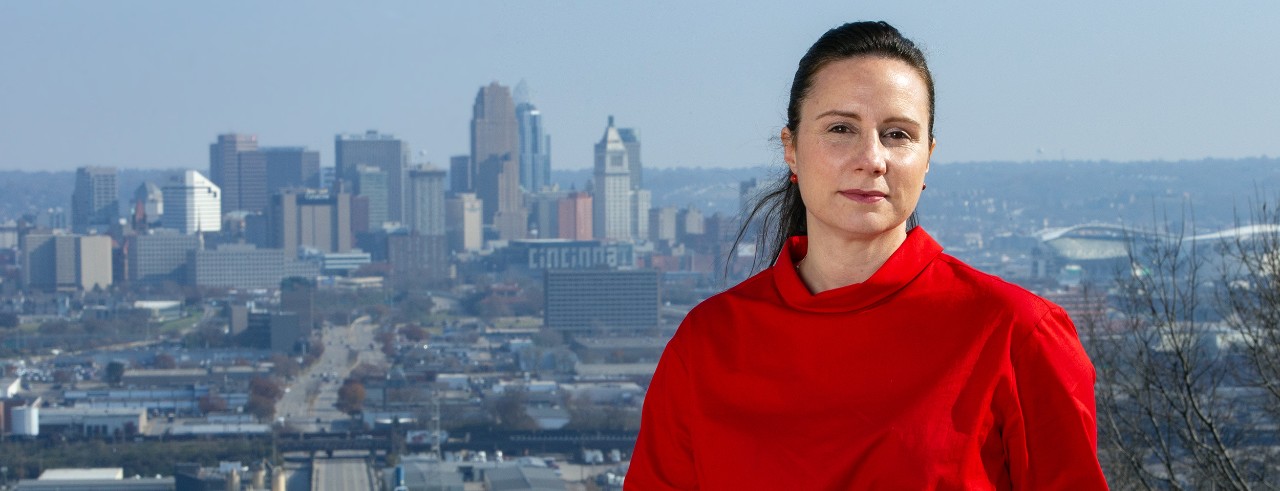 Woman in red shirt poses in front of Cincinnati skyline