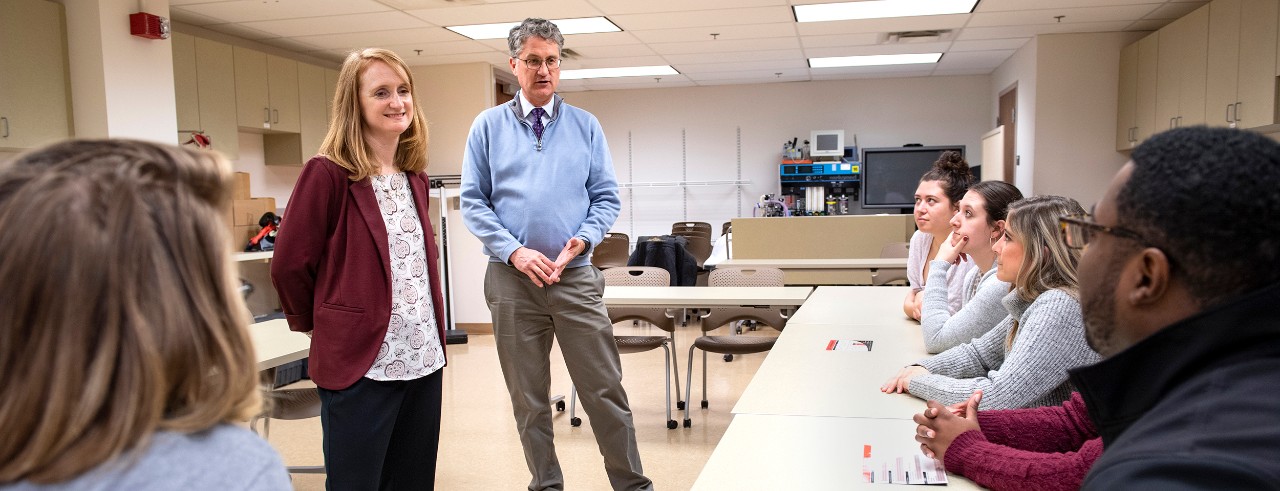 Shauna Acquavita and Michael Brubaker talk to students in a classroom. 