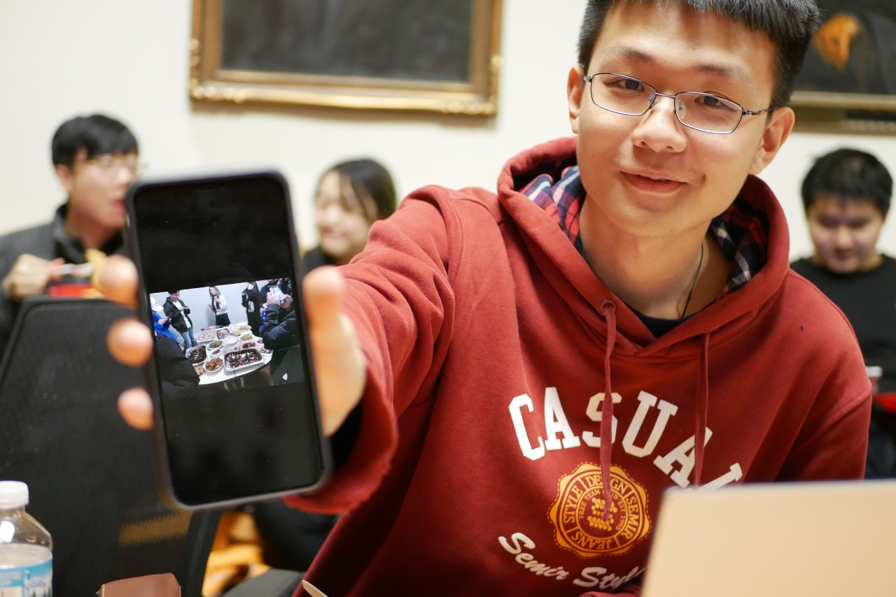 a student shows a photo of a Lunar New Year celebration on his phone