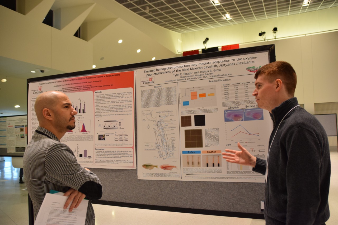 A student discusses his research and poster with a faculty judge.