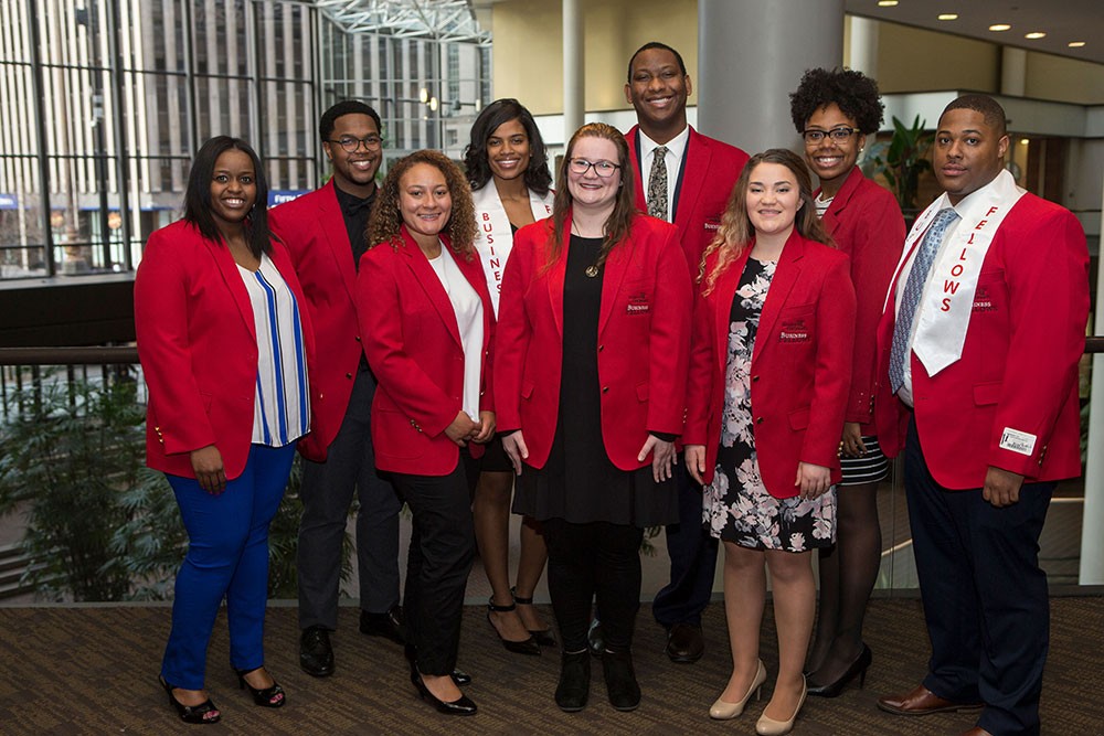 Nine students wearing red blazers posing for a photo