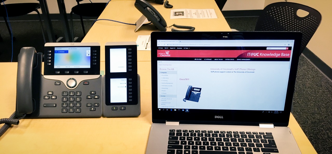 A laptop displays a new phone KB help article while the new phone sits next to the laptop.