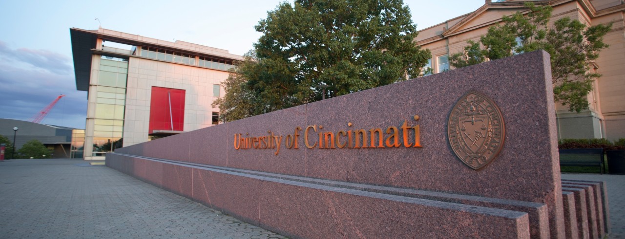 The University of Cincinnati's name and logo on a decorative wall outside a residence hall. 