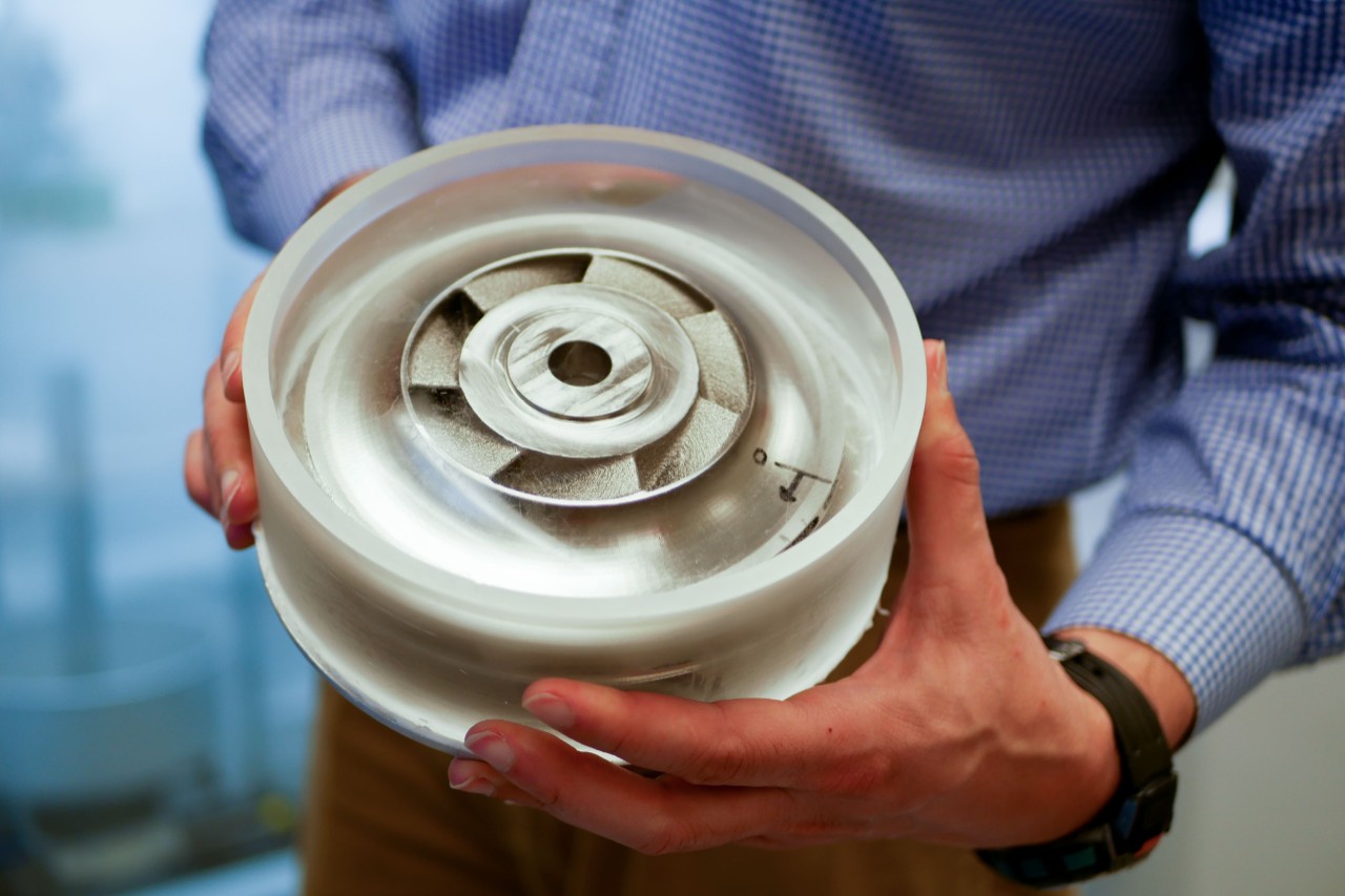 Man holding manufactured part encased in ice 