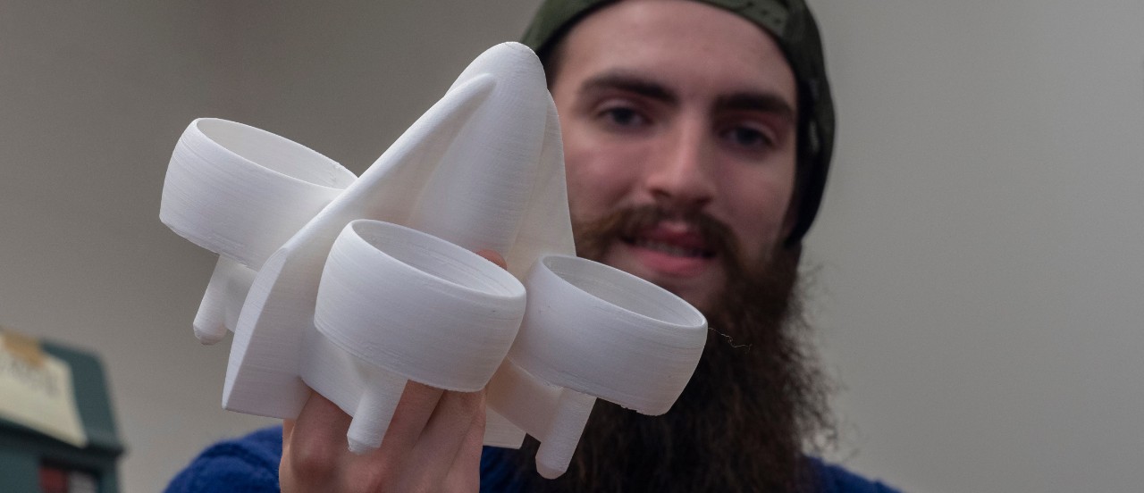 A UC student holds up a 3D-printed model of a flying car.