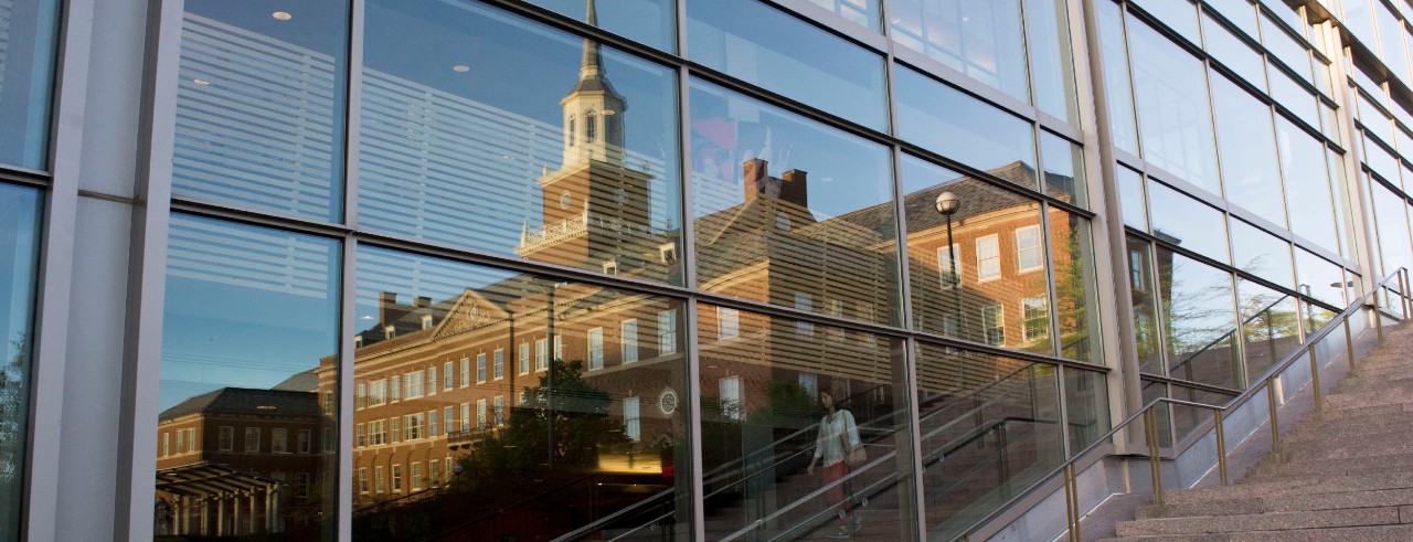 McMicken Hall is reflected in a glass wall.