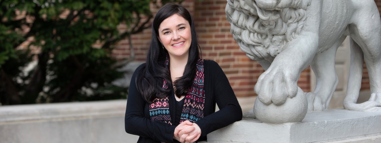 UC student Caitlin Doyle stands in front of Mick and Mack lions at McMicken Hall.